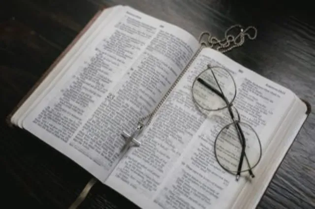 An open Bible with reading glasses resting on it